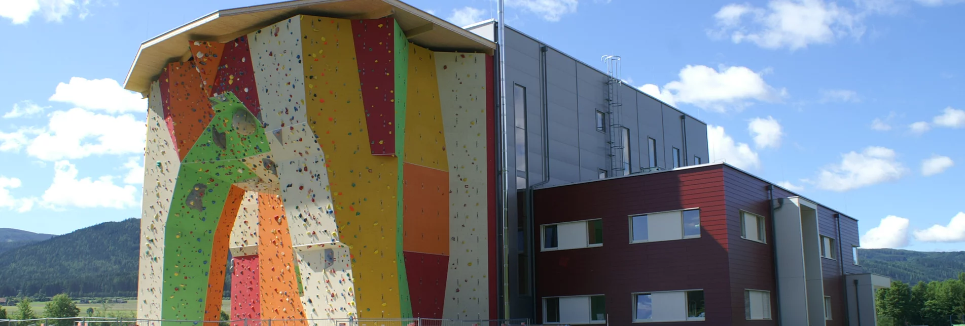 Außenansicht der Kletterakademie in Mitterdorf mit einer großen Kletterwand in bunten Farben