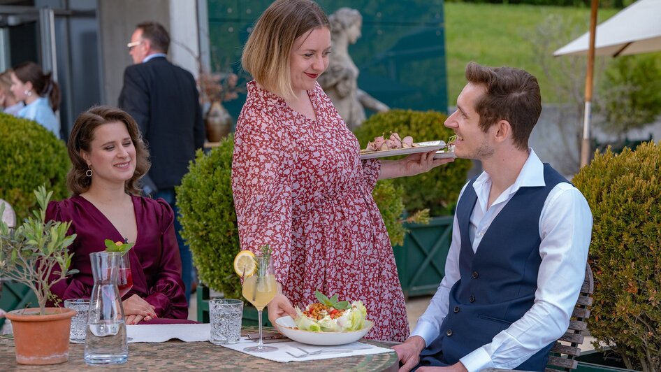 Ein Gast wird im Restaurant aiola im Schloss mit einer Salatschüssel bedient.