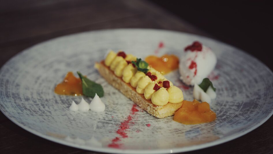 Köstliches Dessert mit Creme, Fruchtgelees und Eis auf einem Teller.