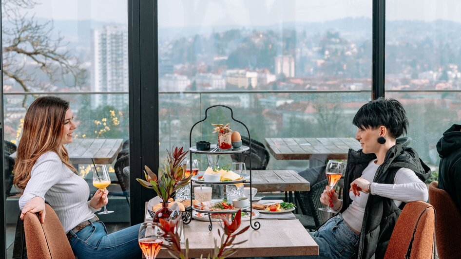 Zwei Frauen genießen Brunch und Cocktails bei aiola upstairs mit Blick auf Graz.