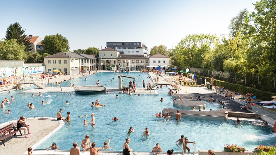Belebtes Augartenbad Graz mit vielen Schwimmern und Sonnenliegen.