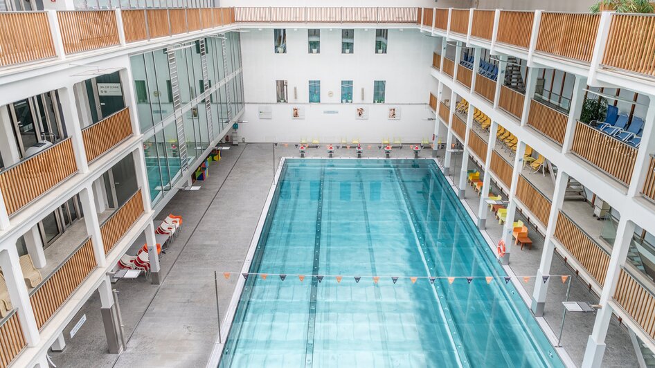 Innenansicht des Schwimmbads Bad zur Sonne in Graz mit Wasserbecken und Sitzen. Die Umgebung ist hell und modern. | © Holding Graz - achtzigzehn