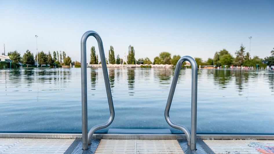Eine Sicht auf das ruhige Wasser des Bad Straßgang mit einer Leiter zum Einstieg. | © Holding Graz - Joel Kernasenko