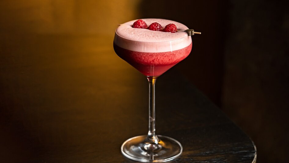 Cocktail mit Himbeeren in einem eleganten Glas, serviert in einer stilvollen Bar. | © Lucija Novak
