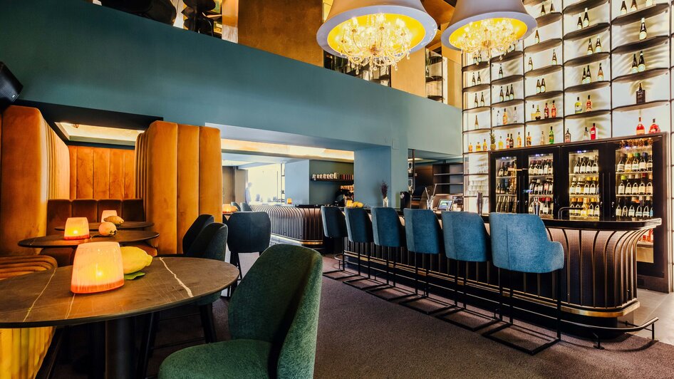 Elegante Bar mit stilvollen Sitzecken und beleuchteten Regalen mit Getränkeflaschen. | © Simon Bauer
