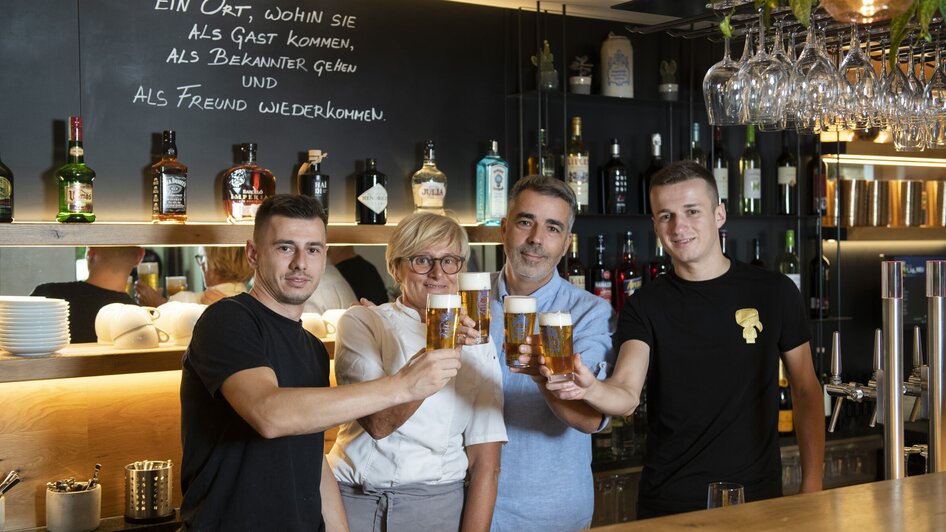 Vier Personen stoßen mit Biergläsern in einem Bistro an. | © Bistro Fino