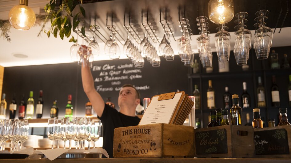Barkeeper im Bistro FINO, Gläser und Weine im Hintergrund. | © Bistro Fino