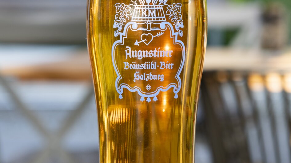 Ein Glas Augustiner Bier auf einem Tisch, umgeben von natürlichem Licht. | © Bistro Fino