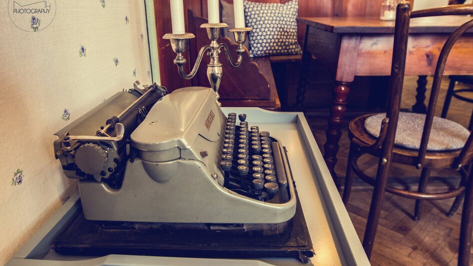 Eine vintage Schreibmaschine auf einem Tisch in einem gemütlichen Café. | © Cafe Fotter
