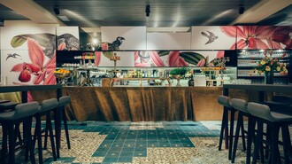 Moderner Barbereich mit floralen Wandmotiven und stilvollen Stühlen. | © Promenade - Joel Kernasenko
