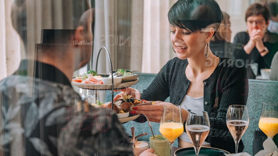 Zwei Personen genießen Speisen und Getränke im Café Promenade in Graz.