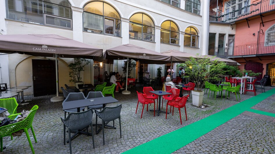 Gemütlicher Innenhof mit bunten Stühlen und Tischen in Graz. | © Ripix