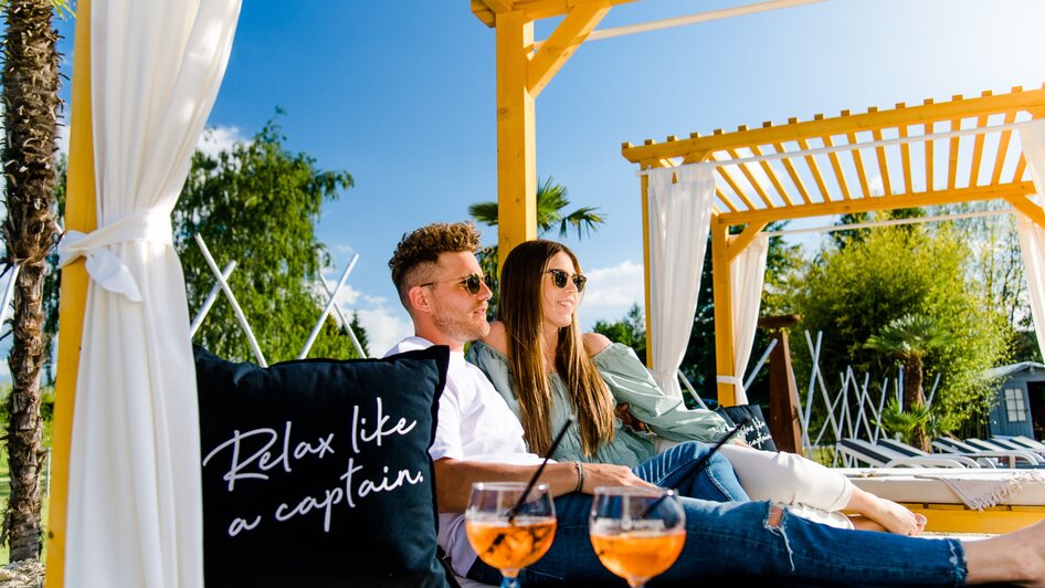 Paar entspannt in einer Lounge mit Cocktails und einer Kissenbotschaft. | © Region Graz - Mias Photoart