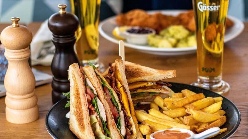 Ein leckeres Sandwich mit Pommes und Getränken auf einem Tisch. | © Das Franz