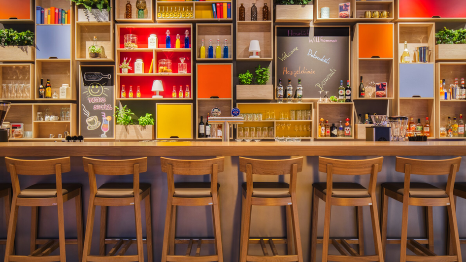Moderne Bar mit Theke, bunten Regalen und Getränken. | © IntercityHotel Graz