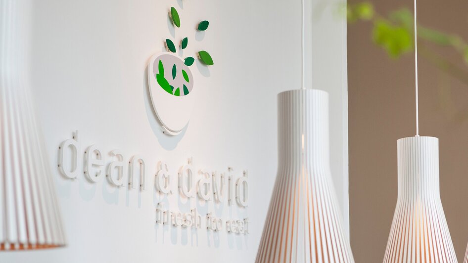 Logo von dean&david mit hängenden Lampen in einem modernen Ambiente. | © dean&david