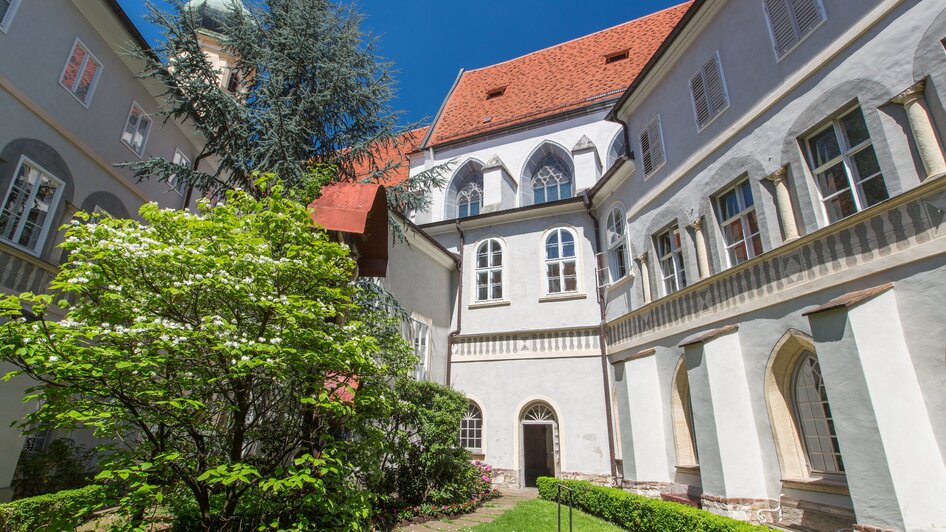 Ansicht des Franziskanerklosters in Graz mit Garten und Gebäuden.