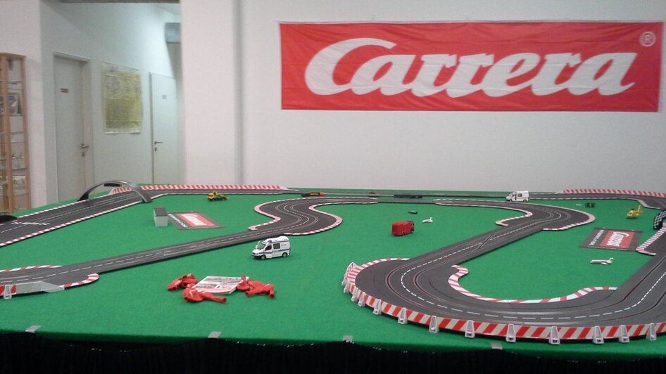 Modellrennstrecke von Carrera mit Autos auf grüner Fläche. | © GATE-08 Flight & Racing Simulation Center e.U. / Herr Marc Asplanato
