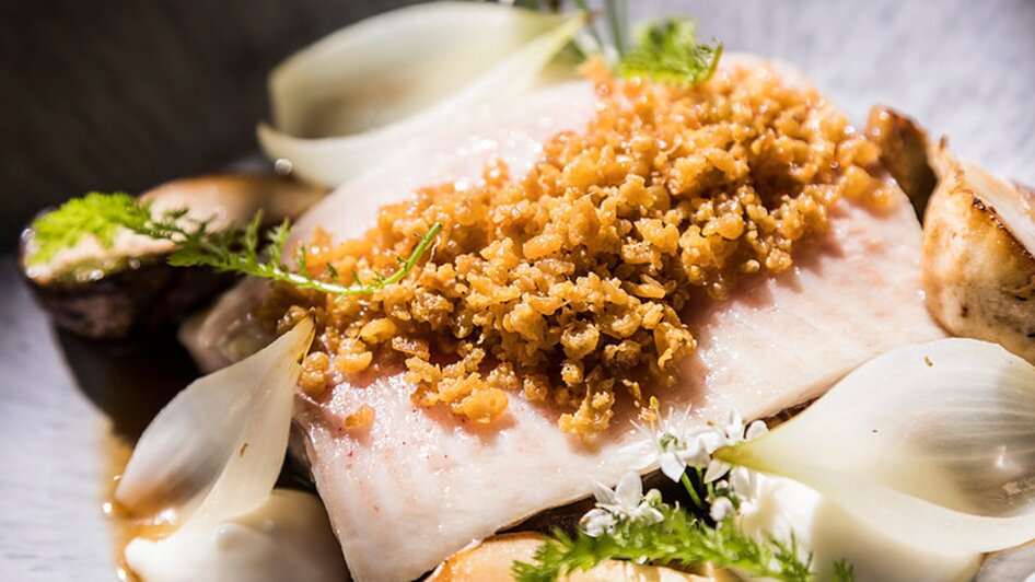 Genießerei am Markt I Essen & Trinken in Graz | © Genießerei am Markt Ein gegrillter Fisch mit knuspriger Kruste, serviert mit Zwiebeln und Kräutern. | © Genießerei am Markt