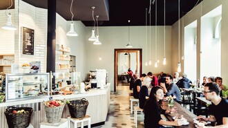 Moderne Café-Atmosphäre mit Gästen, frischen Früchten und Holzinterieur. | © Lupi Spuma 