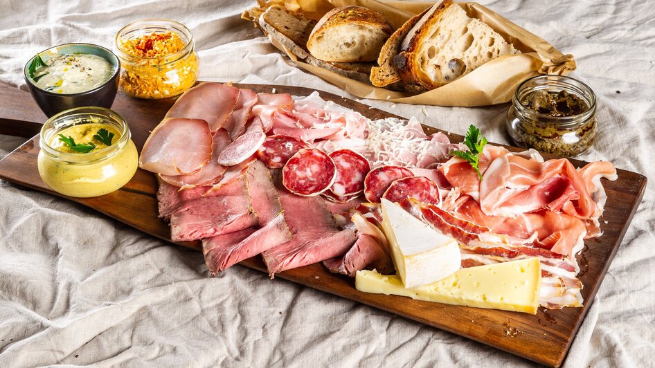 Platte mit Wurst, Käse, Dips und Brot auf einem Tisch. | © Paul Stajan