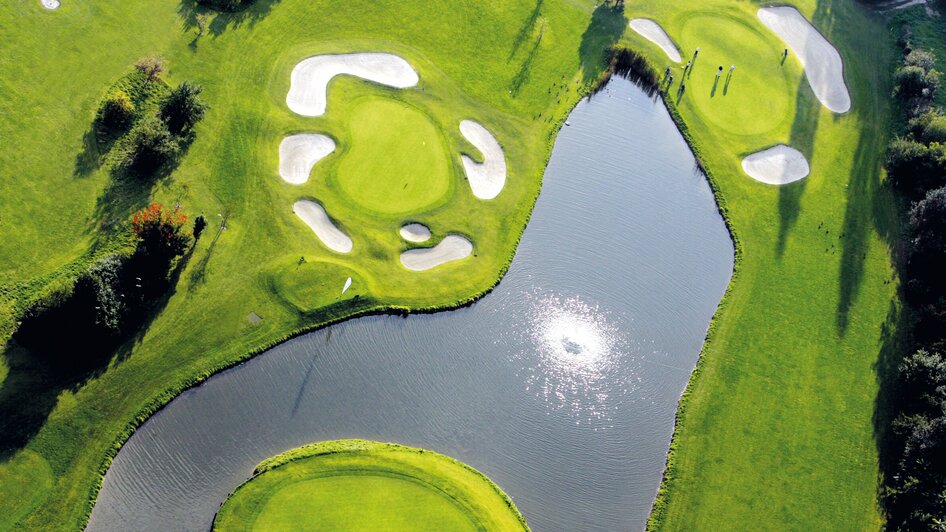 Luftaufnahme eines Golfplatzes mit Wasser und Sandbunkern.