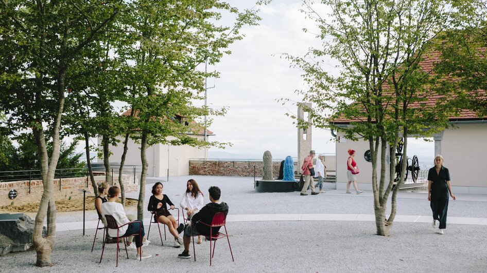 Fünf Personen sitzen im Freien und unterhalten sich am Graz Museum Schlossberg. | © Sebastian Reiser
