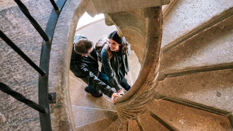 Ein Paar hält sich an der Doppelwendeltreppe in Graz fest. | © Graz Tourismus