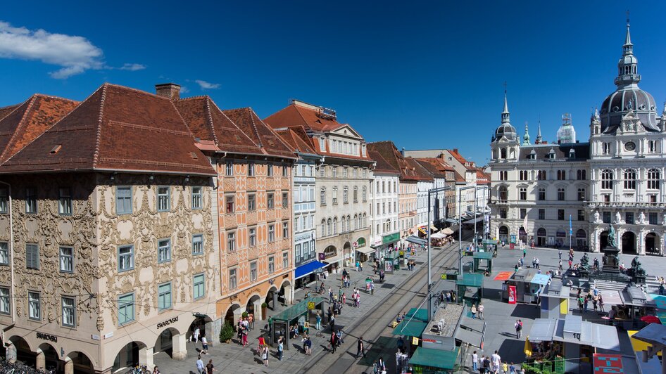 Blick auf den Hauptplatz in Graz mit Marktständen und historischen Gebäuden.