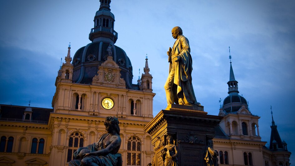 Abendansicht des Rathauses am Hauptplatz in Graz mit Statue.