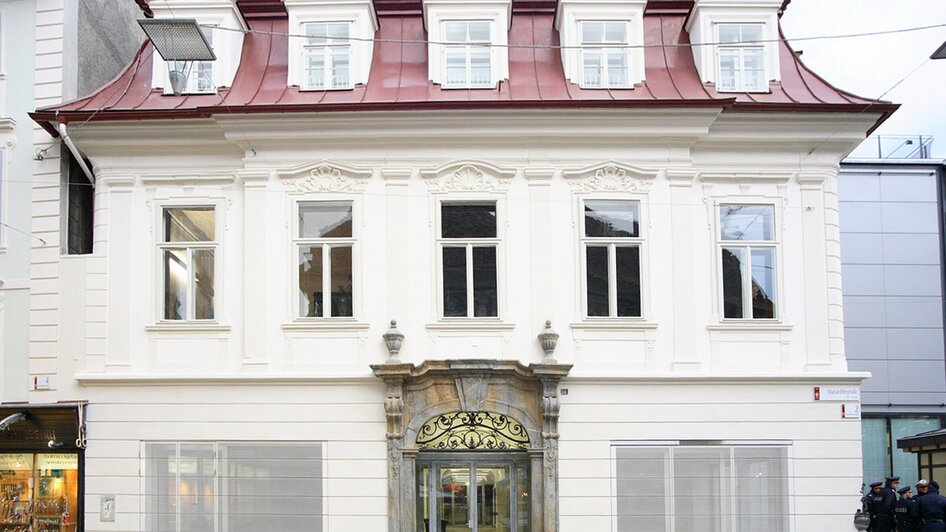 Historisches Gebäude mit rotem Dach und eleganter Fassade in Graz.