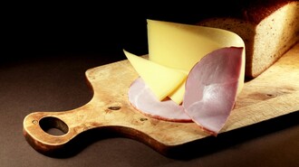 Scheiben von Käse und Schinken mit einem Brot auf einem Holzbrett. | © Sattler