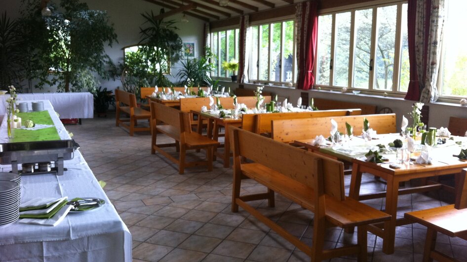 Gemütlicher Speisesaal in der Heurigenschenke Sattler mit Tischen und Pflanzen. | © Sattler