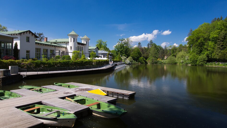 Schöner Blick auf den Hilmlteich in Graz mit Bootsanlegestelle und üppiger Vegetation.