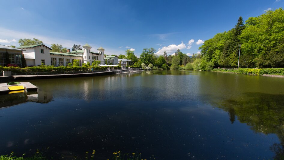 Idyllischer Hilmteich in Graz, umgeben von Bäumen und blauen Himmel.