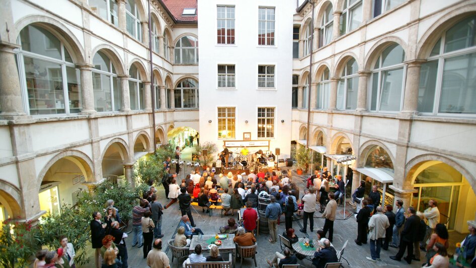 Belebter Innenhof mit Menschen und einer Band bei einem Event im Generalihof. | © Graz Tourismus - Harry Schiffer