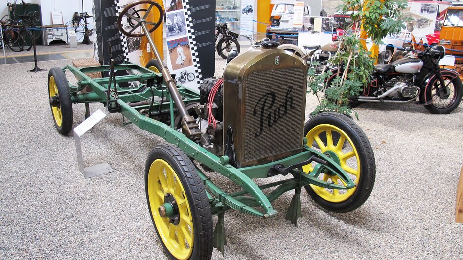 Ein historisches Fahrgestell von Puch mit grünem Rahmen und gelben Rädern in einem Museum. | © Johann Puch Museum