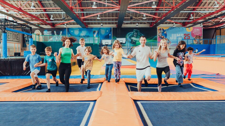 Eine Gruppe von Kindern und Erwachsenen springt auf Trampolinen. | © Lex Karelly