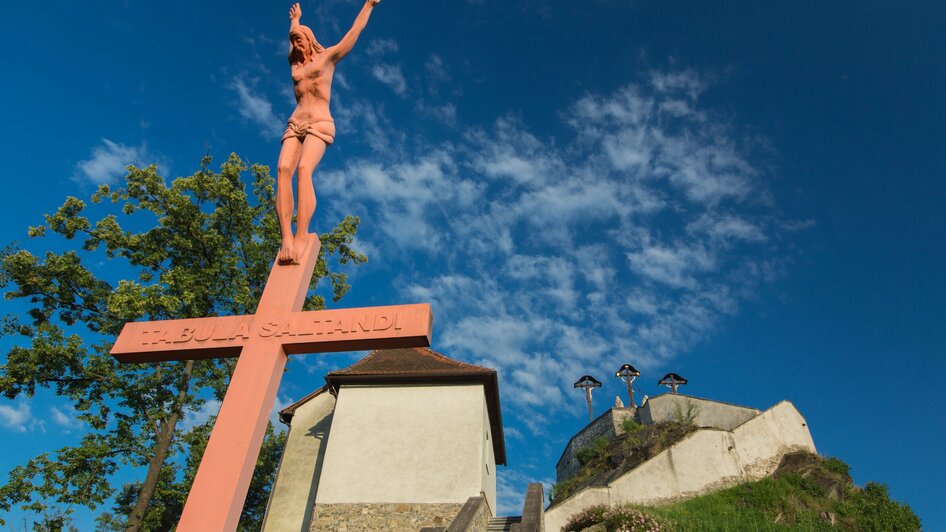 Sicht auf den Kalvarienberg in Graz mit einem Kruzifix und Aussichtsturm.