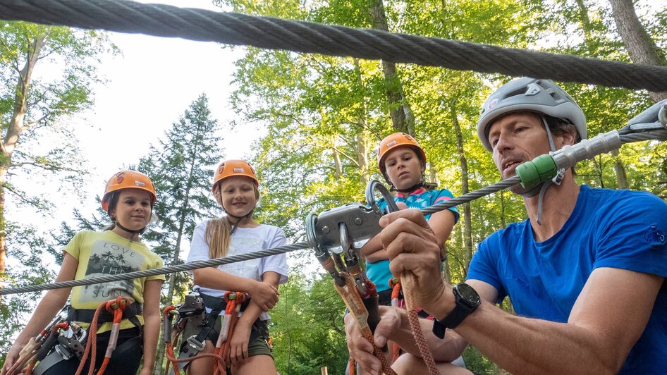 Eine Gruppe von Kindern mit Helmen beobachtet einen Klettertrainer. | © WAP