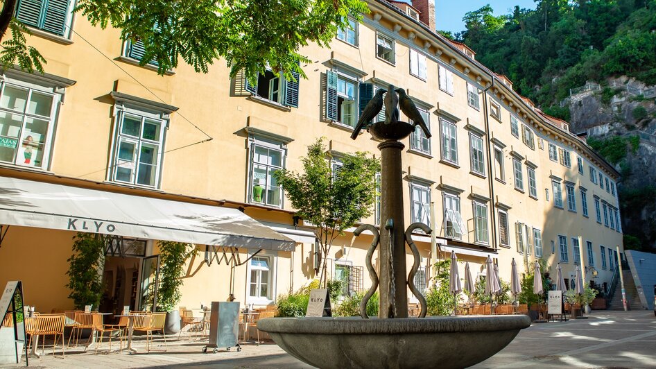 Gemütlicher Platz mit Brunnen und Restaurant KLYO in Graz.