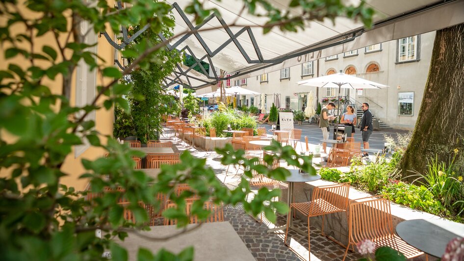 Gemütliche Außenterrasse des KLYO mit Pflanzen und Gästen in Graz.