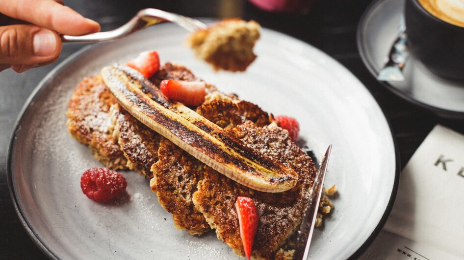 Leckeres Frühstück mit Bananen, Beeren und Kaffee.