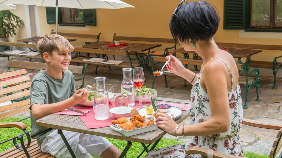 Ein Junge und eine Frau genießen ein Essen im Kreuzwirt am Rosenberg in Graz. | © 5komma5sinne - Helmut Schweighofer