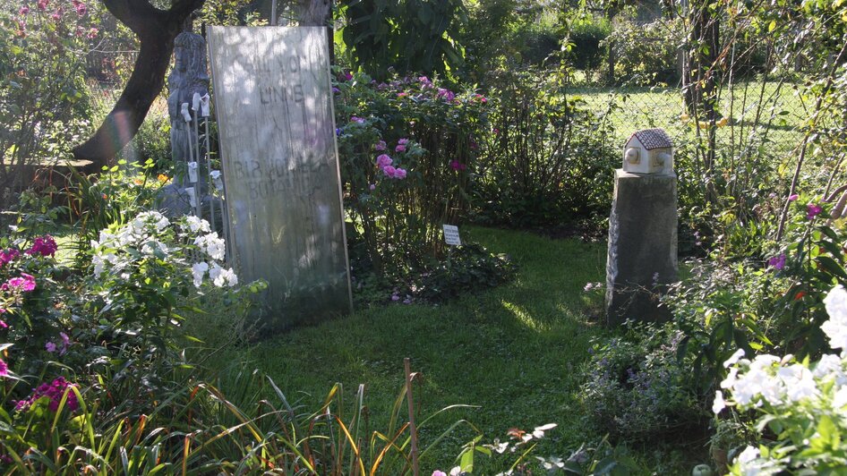 Ein Garten mit Grabsteinen und bunten Blumen.