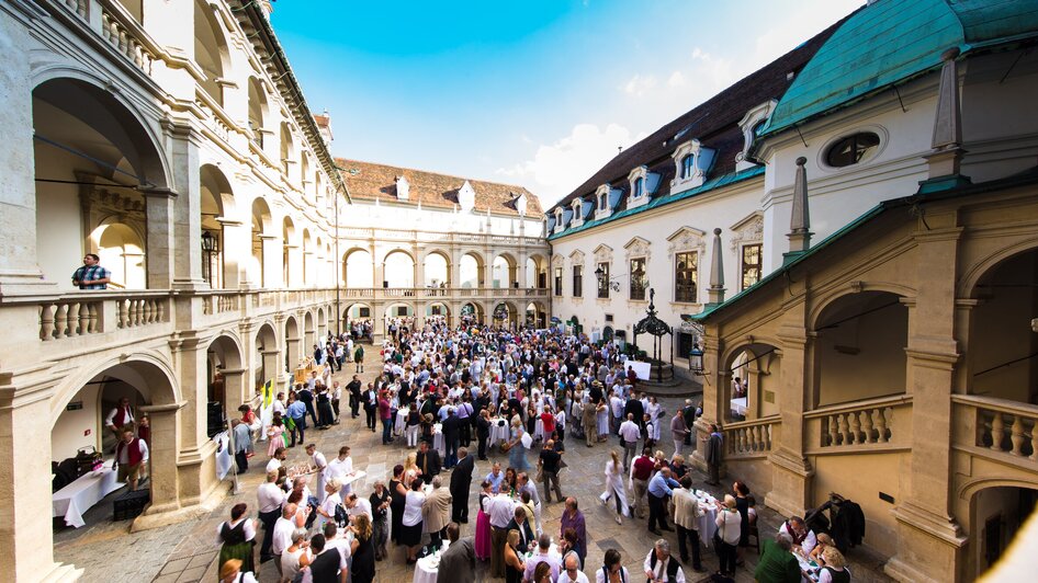 Vielzahl von Menschen im Landhaushof in Graz versammelt - bei der Langen Tafel der GenussHauptstadt.
