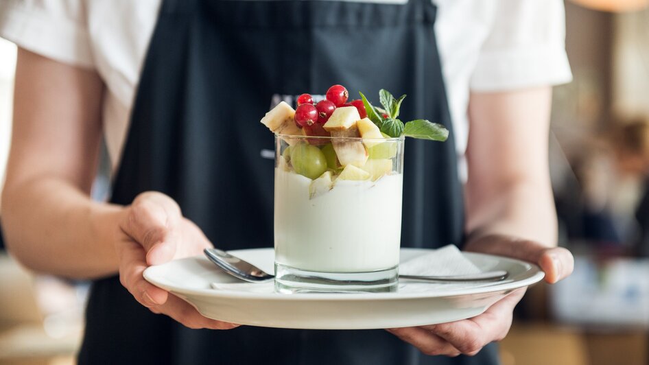 Ein Kellner serviert ein Dessert mit frischen Früchten. | © Martin Auer 