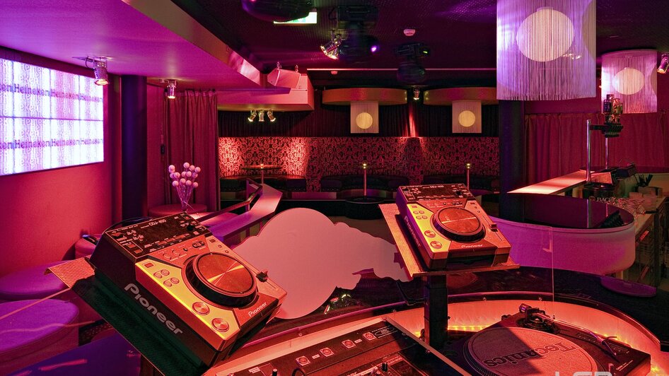 Einblick in einen stilvollen Club mit DJ-Equipment und bunten Lichtern. | © Mausefalle +