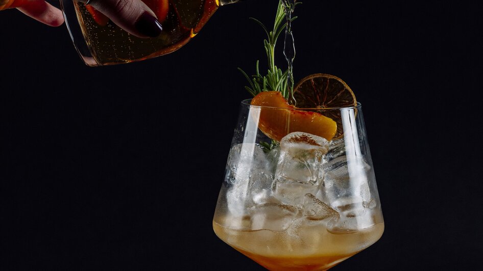 Ein Cocktail wird in ein großes Glas mit Eis gegossen. | © Simona Donko