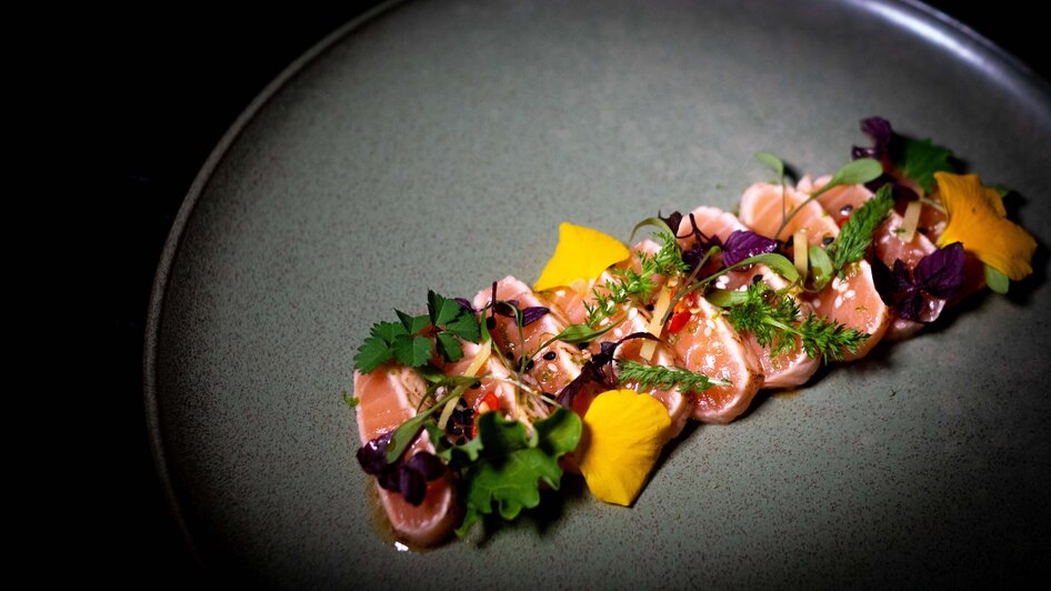 Delikate Fischplatte mit frischen Kräutern und essbaren Blüten.